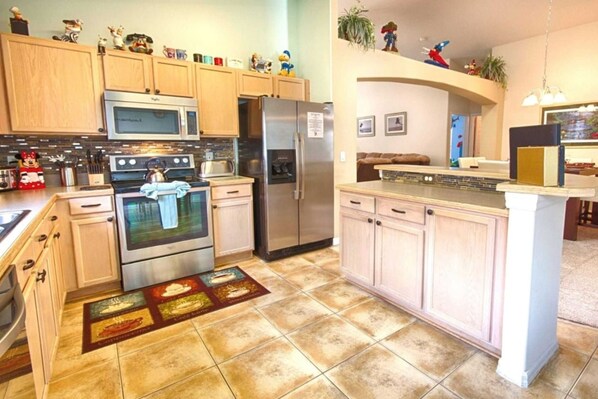 A kitchen with wooden cabinets, stainless steel appliances, and a tiled floor.