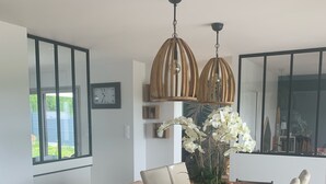 Ein Essbereich mit Holztisch, beigen Stühlen, einer Topforchidee und Pendelleuchten.