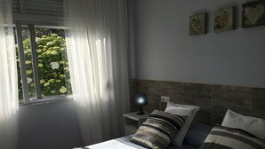 A bedroom with a bed, a nightstand, a lamp, a window with sheer curtains, and a view of greenery outside. - Country house with gate next to the sea (Santa Marta de Ortigueira)