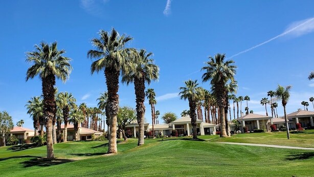 A golf course with palm trees and resort buildings. - PGA WEST PALMER GATE - 9TH HOLE - JUST FORE FUN  (La Quinta)