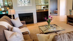 A living room with a sofa, a glass coffee table, and a fireplace. - PGA WEST PALMER GATE - 9TH HOLE - JUST FORE FUN  (La Quinta)