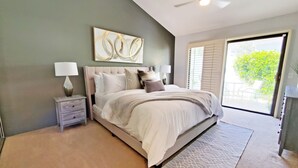 A bedroom with a bed, nightstands, a ceiling fan, and a view of the outdoors. - PGA WEST PALMER GATE - 9TH HOLE - JUST FORE FUN  (La Quinta)