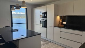 Een moderne keuken met een groot eiland, inbouwapparatuur en uitzicht op zee.