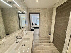 A modern bathroom with a large mirror, two sinks, and a wooden door.