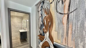 Een gang met een moderne badkamer, inclusief een wastafel en spiegel.