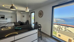 Een moderne keuken met een groot eiland, hanglampen en uitzicht op zee.