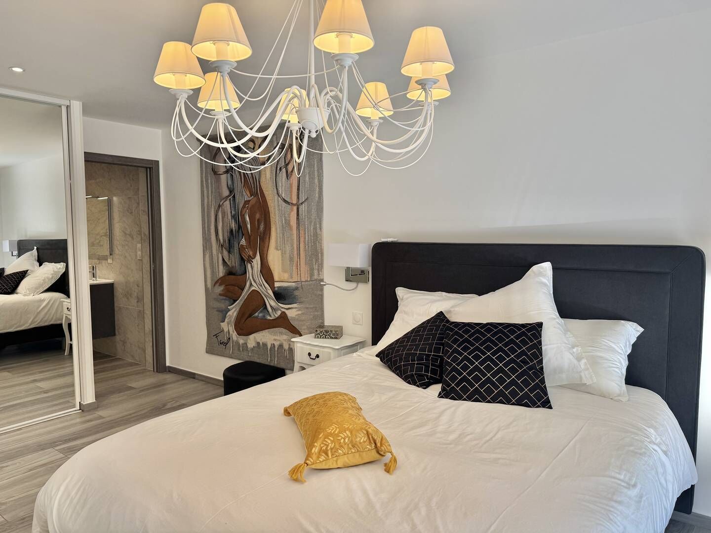 Una habitación de hotel moderna con una cama grande, una araña y un cuadro en la pared.