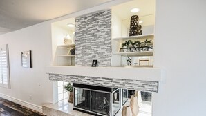 A modern living room with a fireplace, built-in shelves, and a patterned wall. - SVS: Spacious 6BD Vegas Home | Private Pool, BBQ & Game Room | Sleeps 12 (Henderson)