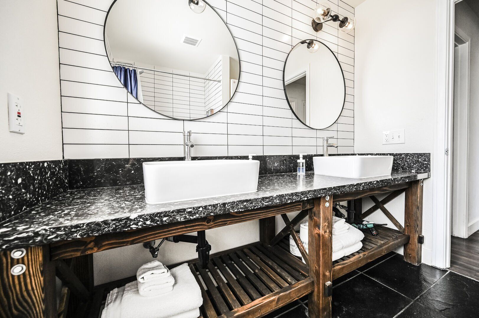 Ein Badezimmer mit zwei Waschbecken, einem Holz-Waschtisch und einem Spiegel.