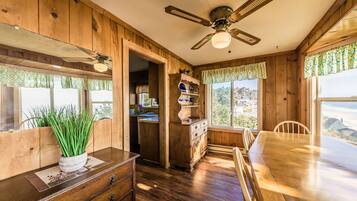 A wooden interior with a dining table, chairs, a ceiling fan, and a view of the outdoors.
