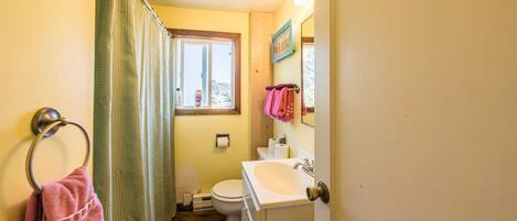 Un baño pequeño con inodoro, lavamanos y cortina de ducha.