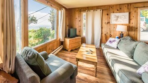 Una sala de estar acogedora con paredes de madera, un sofá, una mesa de centro y un televisor.