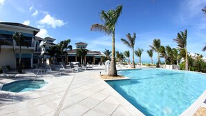 Ein Poolbereich eines Resorts mit mehreren Pools, Liegestühlen und Palmen.