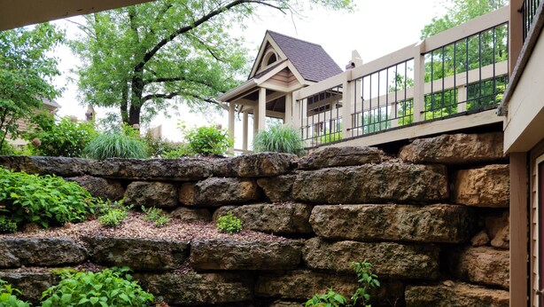 A stone retaining wall with greenery, a wooden deck, and a house in the background. - 1 Bedroom, 1 bath townhouse in The Galena Territory. (Galena)