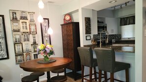 A dining area with a round wooden table, four chairs, and a vase of flowers. A kitchen is visible in the background with a sink and countertop. - 1 Bedroom, 1 bath townhouse in The Galena Territory. (Galena)
