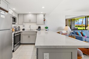 A modern kitchen with grey cabinets, stainless steel appliances, and a large island.
