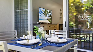 A dining table set with plates, cutlery, and glasses, with a painting of a beach scene above it.