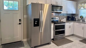 A modern kitchen with stainless steel appliances, white cabinetry, a built-in oven, and a coffee maker.