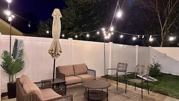 Un espace extérieur aménagé en terrasse, avec des meubles en osier, une table à manger et des guirlandes lumineuses.