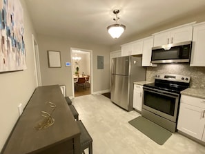 Enjoy cooking in this well-equipped kitchen with stainless steel appliances, white cabinetry, and a granite countertop.