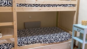 Una cama litera con un edredón estampado, una mesita y un cuadro en la pared.