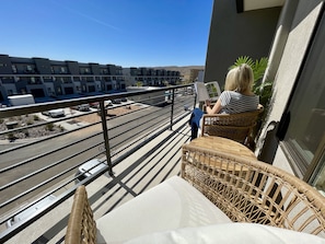 Relax on the balcony with a view of the surrounding neighborhood, featuring comfortable wicker furniture and a peaceful atmosphere.