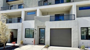 A modern multi-story building with a flat roof, large windows, and a garage. - Trendy 5 BD/4.5 BA St. George Townhome at The Vue (St. George)