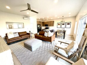Relax in this stylish living space with a central seating area, dining table, and fully equipped kitchen.