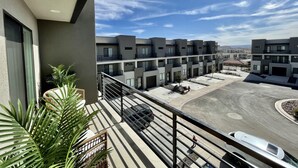A modern apartment complex with multiple balconies, a parking area, and a clear view of the sky. - Trendy 5 BD/4.5 BA St. George Townhome at The Vue (St. George)
