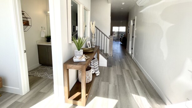 A hallway with a wooden console table, a mirror, and a staircase leading to another room. - Trendy 5 BD/4.5 BA St. George Townhome at The Vue (St. George)