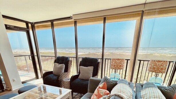 En rymlig balkong med utsikt över havet, inredd med en soffa, fåtöljer och ett soffbord.