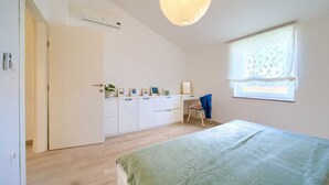Ein Schlafzimmer mit Bett, Schreibtisch und einem Fenster mit Vorhang.