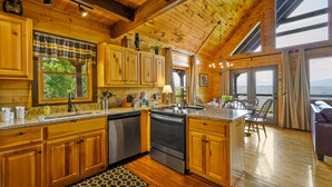 A spacious kitchen with wooden cabinets, a central island, and a view of the outdoors. - HUGE AMAZING Mtn Views!  Great Location! Hot Tub! Game Room! Spacious! Privacy! (Sevierville)