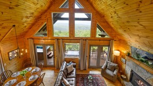 A spacious wooden cabin with a high ceiling, large windows, a fireplace, and a dining area. - HUGE AMAZING Mtn Views!  Great Location! Hot Tub! Game Room! Spacious! Privacy! (Sevierville)