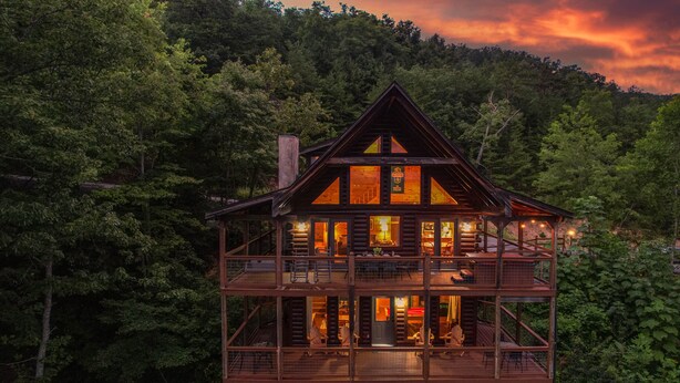 A multi-level wooden cabin with a balcony, surrounded by dense forest. - HUGE AMAZING Mtn Views!  Great Location! Hot Tub! Game Room! Spacious! Privacy! (Sevierville)