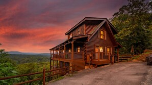 A wooden cabin with a balcony, surrounded by a wooden fence, set against a scenic backdrop. - HUGE AMAZING Mtn Views!  Great Location! Hot Tub! Game Room! Spacious! Privacy! (Sevierville)