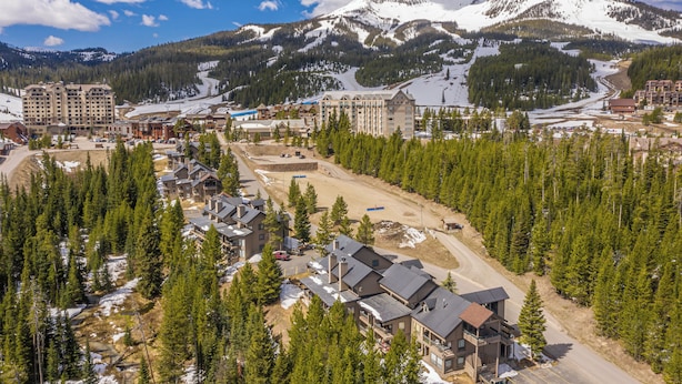 Een wintersportgebied met meerdere gebouwen, waaronder een groot hotel met meerdere verdiepingen en een kleiner chalet.