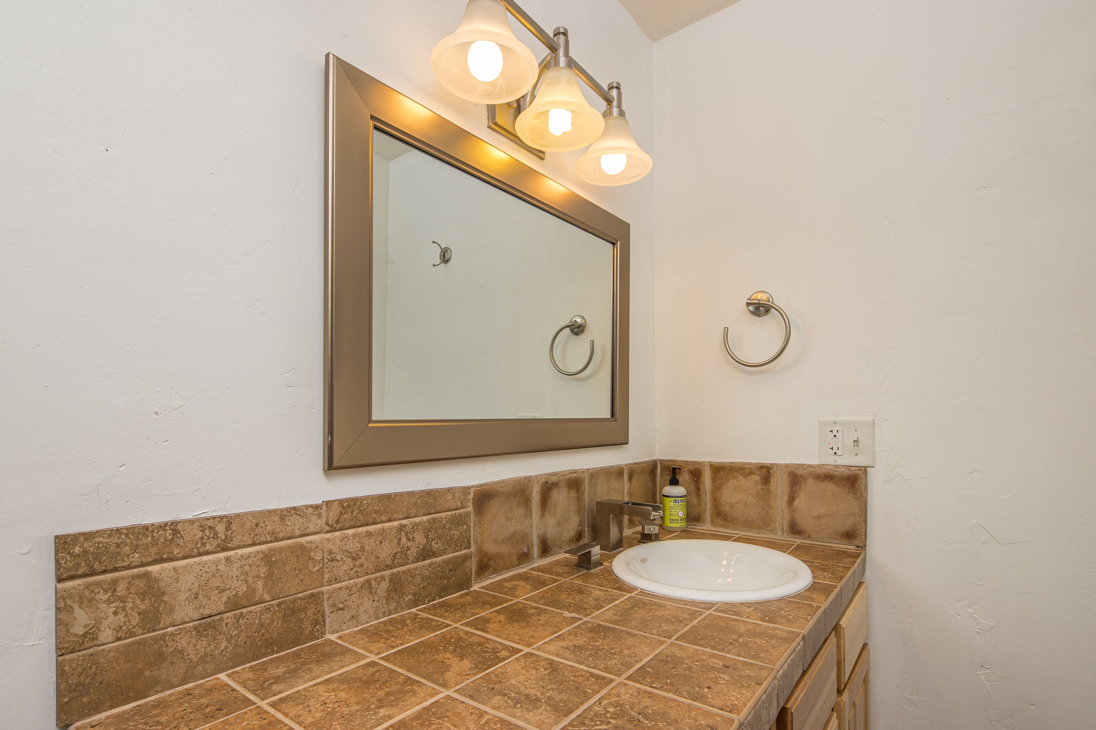 A bathroom with a large mirror, a sink, and a towel ring.