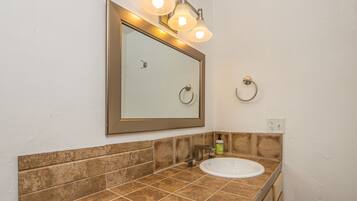 A bathroom with a large mirror, a sink, and a towel ring.