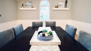 Ein Esszimmer mit einem schwarzen Tisch, weißen Tischdekorationen und blau gepolsterten Stühlen.