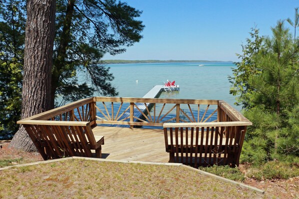 A wooden deck with two benches overlooking a calm lake.