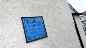 En skylt på en byggnadsvägg som annonserar för "Railway Cottages", fristående semesterbostäder.