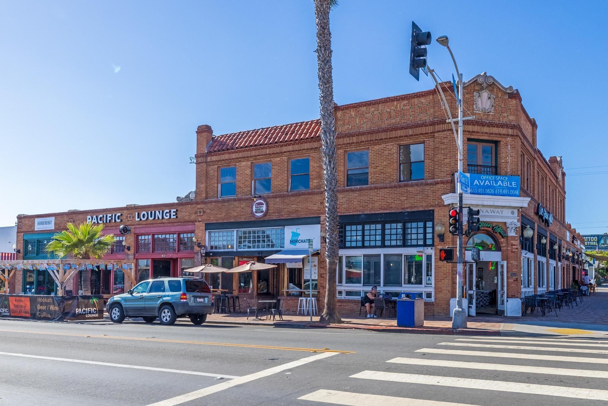 A street view with a Pacific Lounge building, a sign for office space availability, and a tattoo shop.
