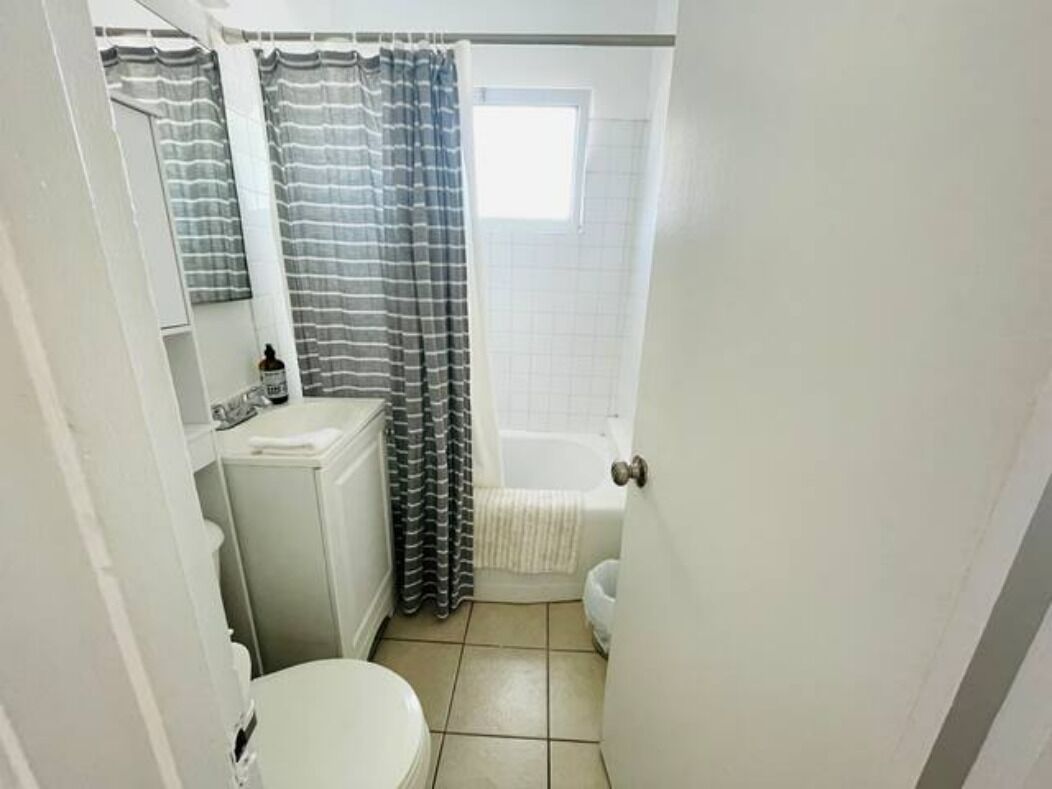 A small, compact bathroom with a toilet, sink, and shower area.