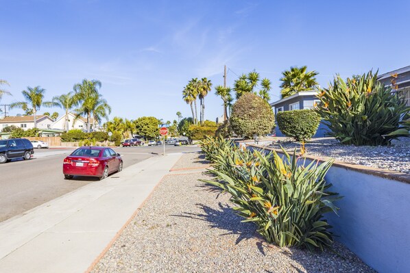 A street with palm trees, a red car, and a stop sign.