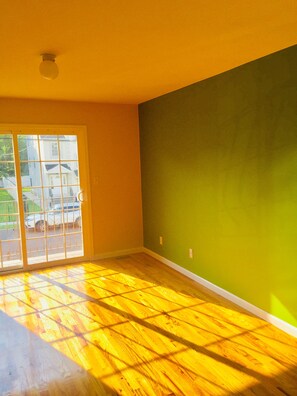 Une pièce dotée d’une grande porte-fenêtre coulissante, d’un plancher en bois et d’un mur vert.