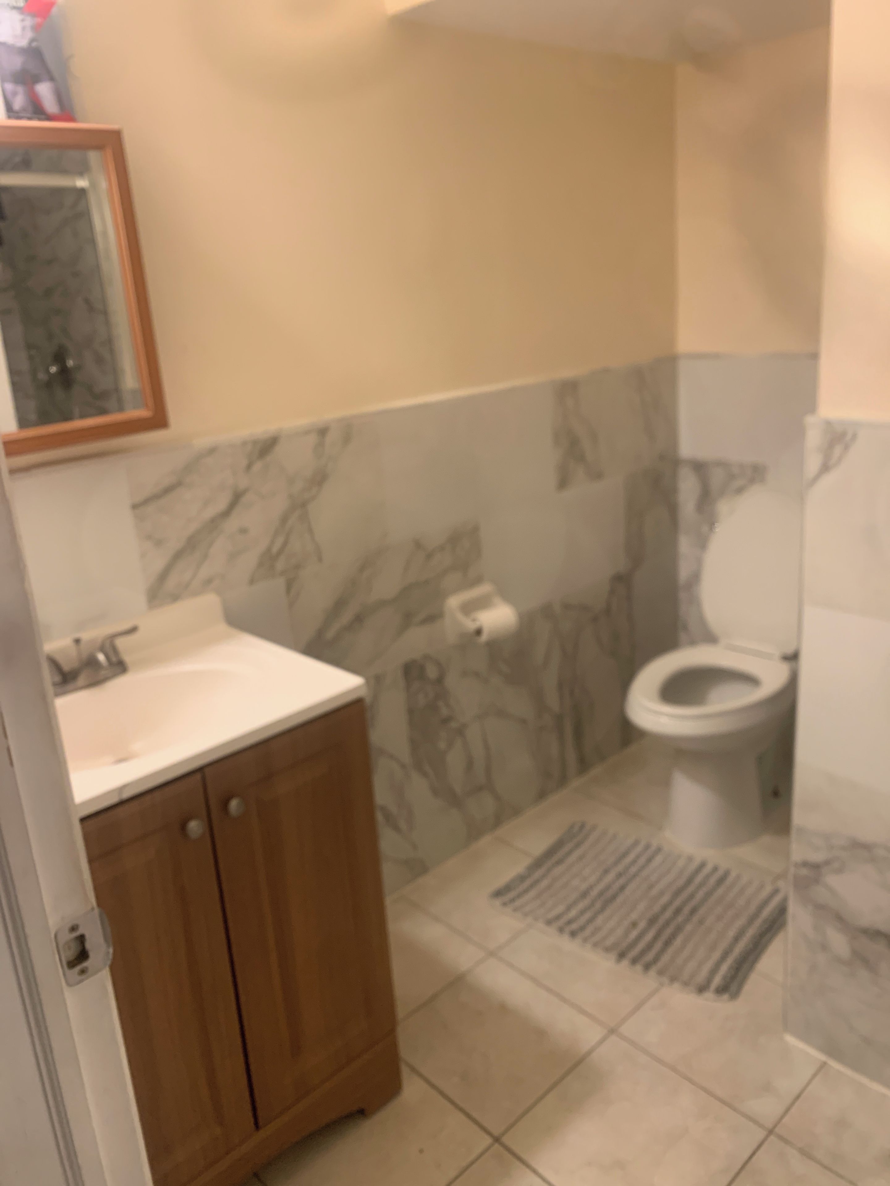 Ein Badezimmer mit Holzschrank, Waschbecken, Toilette und Duschbereich.