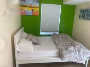 Un lit simple avec un matelas blanc, deux oreillers et une couverture à motifs floraux.