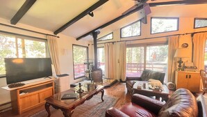 A spacious living room with a large flat-screen TV, leather sofa, and a wooden coffee table. - ManVee Lodge at Yosemite - Just 2 miles from the south gate entrance to Yosemite (fish camp)