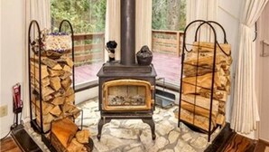 A cozy room with a stone fireplace, a wooden ceiling, and large windows. - ManVee Lodge at Yosemite - Just 2 miles from the south gate entrance to Yosemite (fish camp)